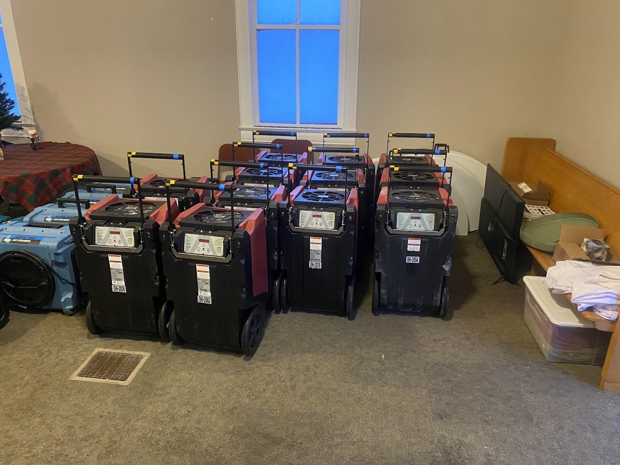 Lineup of commercial dehumidifiers and air movers staged for a Binnacle drying job