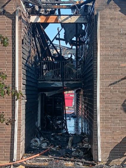 Interior corridor showing fire and smoke damage with debris on the floor