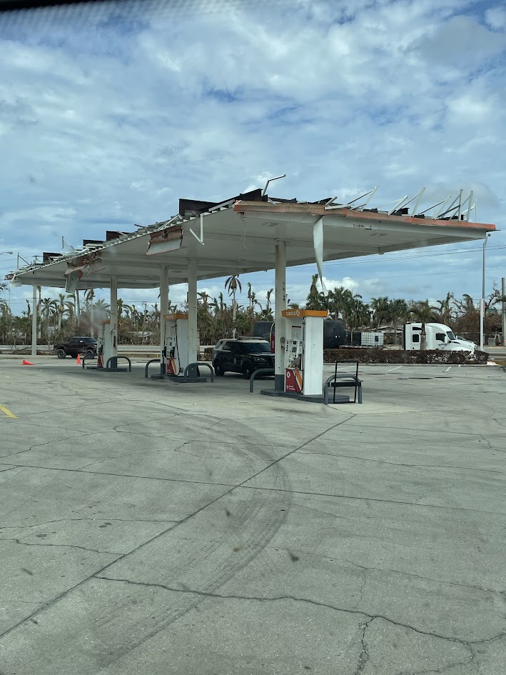Hurricane-damaged gas station with collapsed canopy and exposed framing