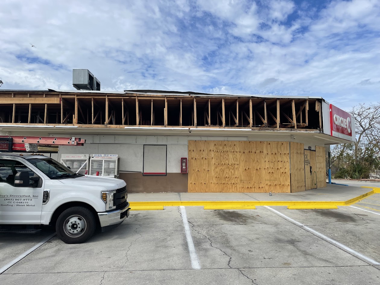 Hurricane-damaged storefront with exposed framing and roof loss