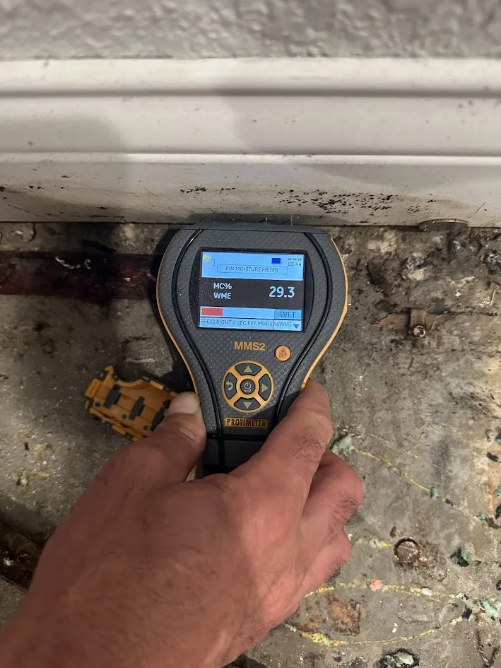 Binnacle technician taking a moisture reading at a water-damaged baseboard