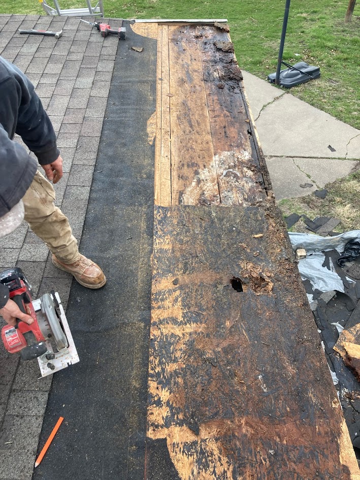 Roofer cutting away rotted decking on a residential roof