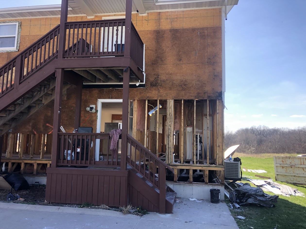 Two-story home with storm-stripped siding exposing structural sheathing
